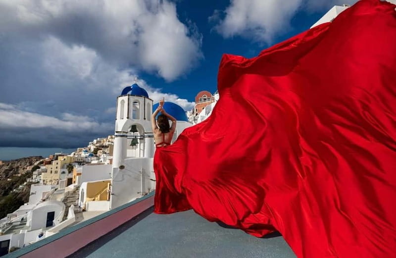 Santorini: Flying Dress Photoshoot <strong>Dress Included</strong> – Key points before you go’ /></p>
<ul>
<li><strong>Dress rental included</strong> (1 flying dress per lady) with 15 color choices from an emailed catalog</li>
<li><strong>35–70 professionally edited photos</strong> delivered by link in 7–10 days, depending on the option</li>
<li><strong>Assistant helps the dress fly</strong> so you get real motion, not just a still pose</li>
<li><strong>Oia-only for the 1-hour</strong> option, plus up to 2 extra villages for the 3-hour option</li>
<li><strong>2–3 phone videos</strong> shot on the day, alongside your edited photos</li>
<li><strong>Private group</strong> with multilingual guidance (English, Greek, Polish, Romanian)</li>
</ul>
<h2 id="a-wind-tossed-gown-in-oia-the-core-idea">A Wind-Tossed Gown in Oia: The Core Idea</h2>
<p><img width="800" height="504" decoding="async" src=